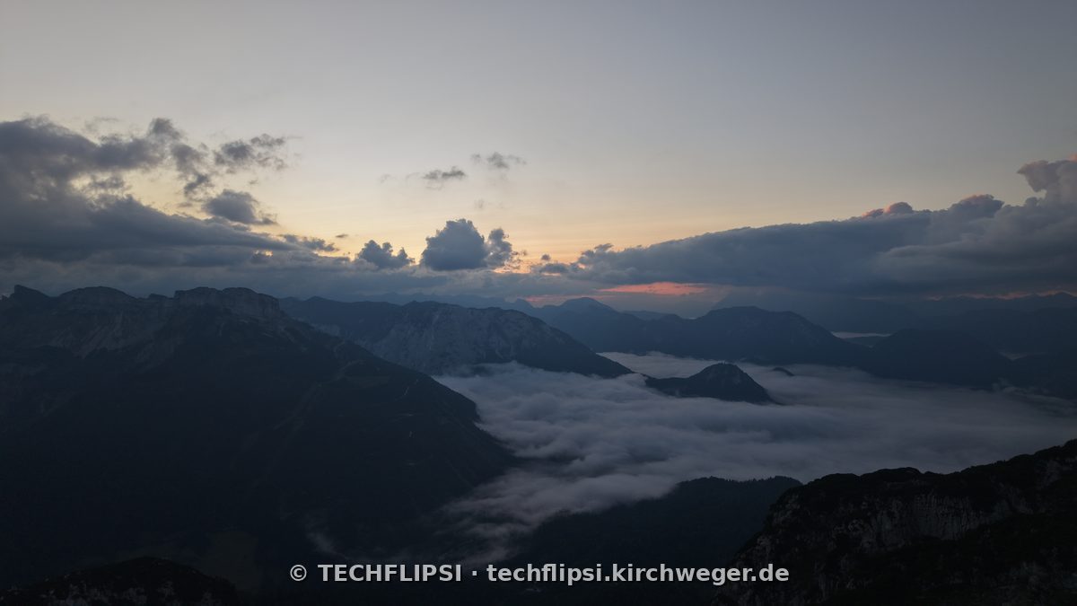 Blick über die Wolkeninversion am Sandling, dichtes Nebelmeer, darüber dunkle Gipfel im ersten Licht.